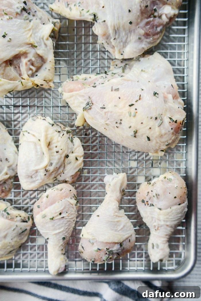 Marinated chicken pieces draining on a wire rack over a baking sheet.