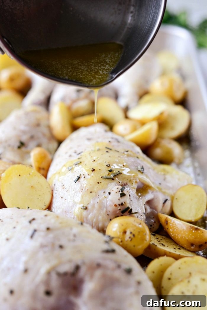 Melted butter and olive oil being drizzled over the chicken and potatoes in the roasting pan.