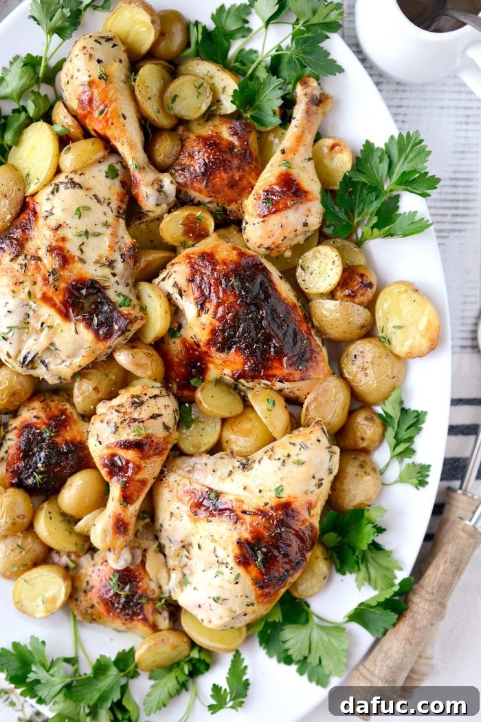 Close-up of roasted chicken and potatoes on a plate, being drizzled with lemon-infused pan drippings.