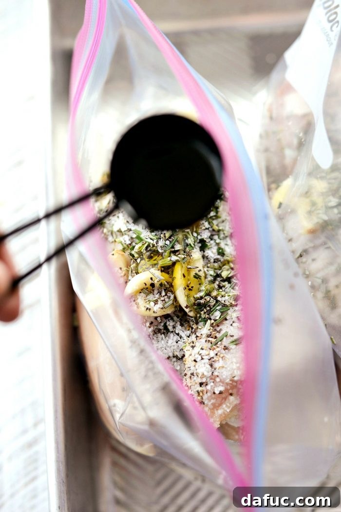 Garlic, rosemary, salt, and pepper being added to a bag of chicken.