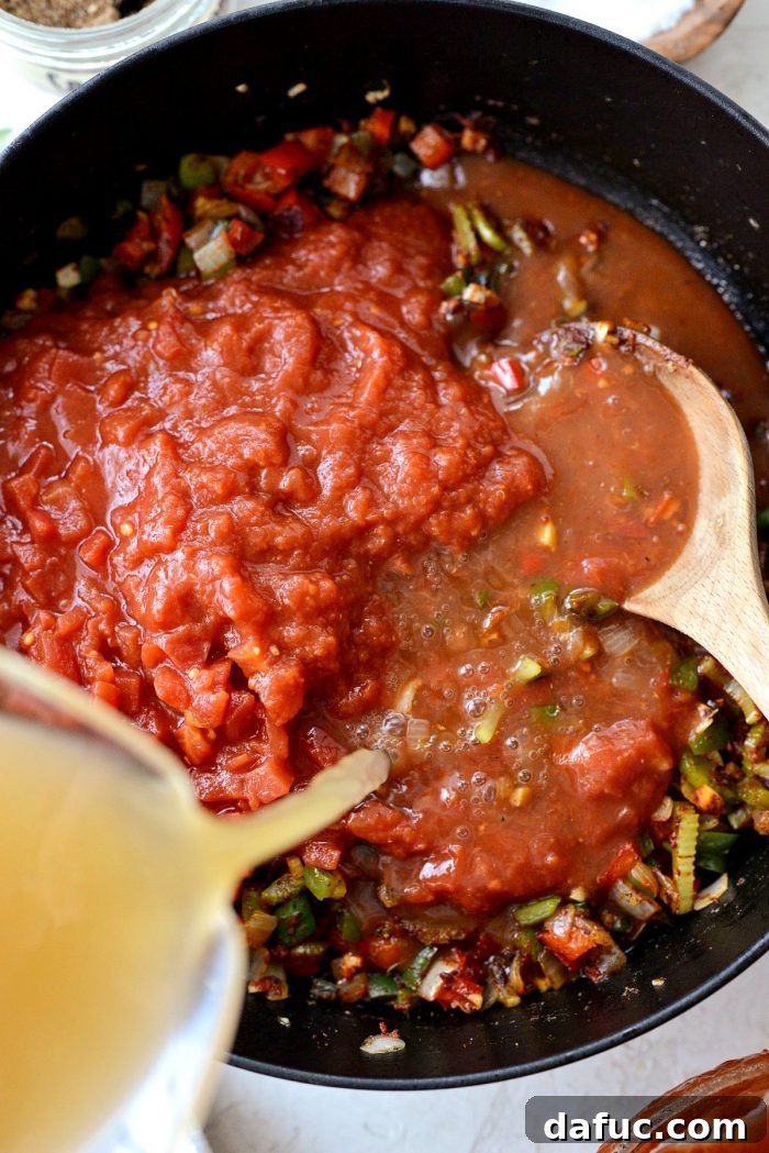 Effortless One-Pot Jambalaya 14 Canned crushed tomatoes, diced tomatoes, and chicken stock poured into the skillet, forming the liquid base for the jambalaya.
