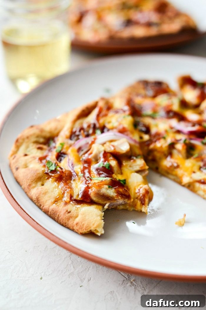 A final close-up of a single slice of BBQ Chicken Naan Pizza, ready to be picked up and enjoyed.