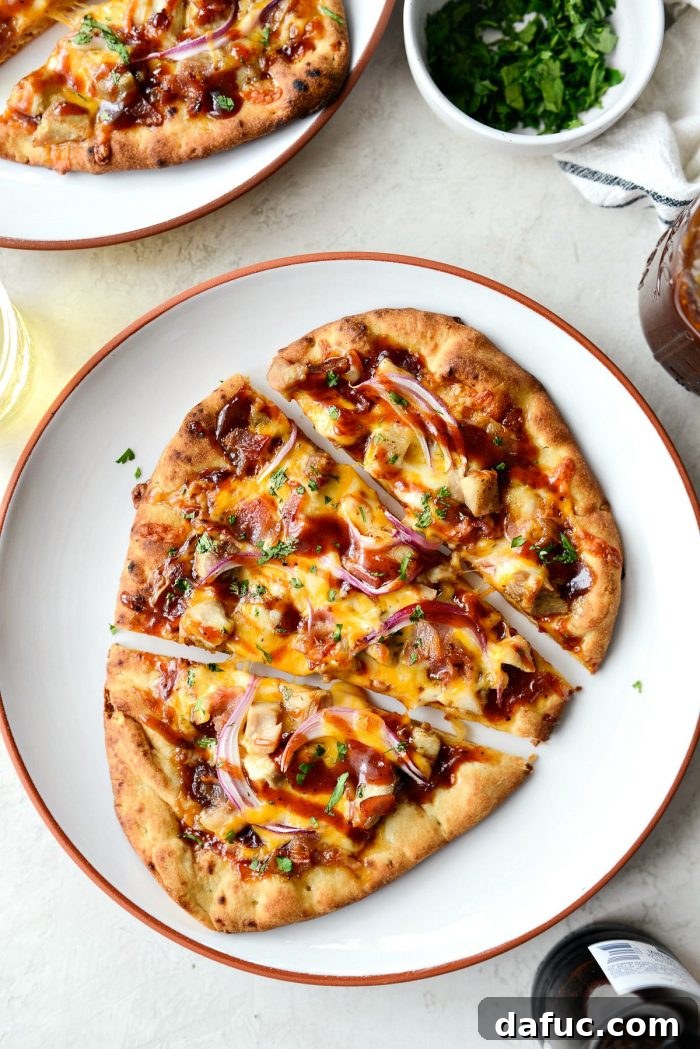 A close-up of a slice of BBQ Chicken Naan Pizza, showing the perfectly melted cheese and toppings.