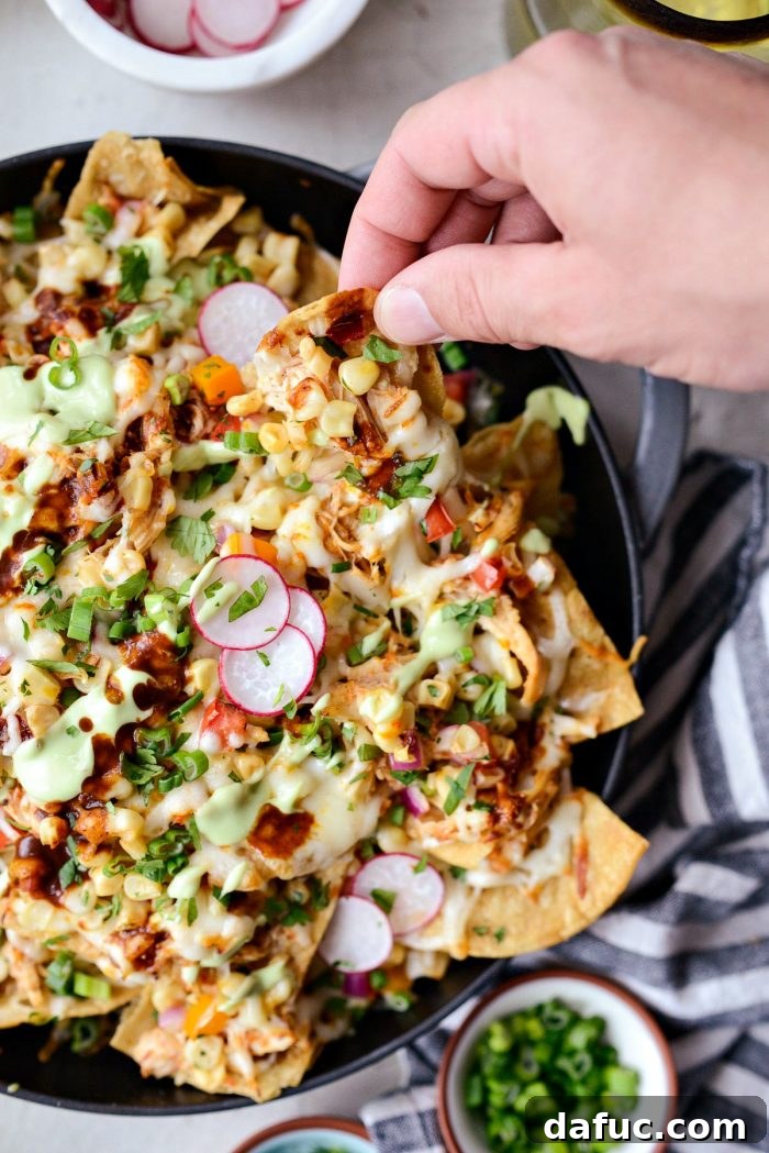 Golden Lava Chicken Nachos 11 Fully garnished Jacuzzi Chicken Nachos, finished with a generous drizzle of creamy avocado crema and a sprinkle of vibrant radish slices, ready to be served.