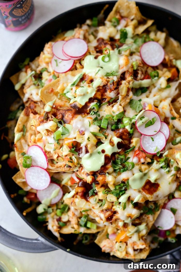 Golden Lava Chicken Nachos 13 An irresistible cheese pull from a hot Jacuzzi Chicken Nacho, showcasing the perfectly melted Muenster cheese stretching from the pan to the chip.