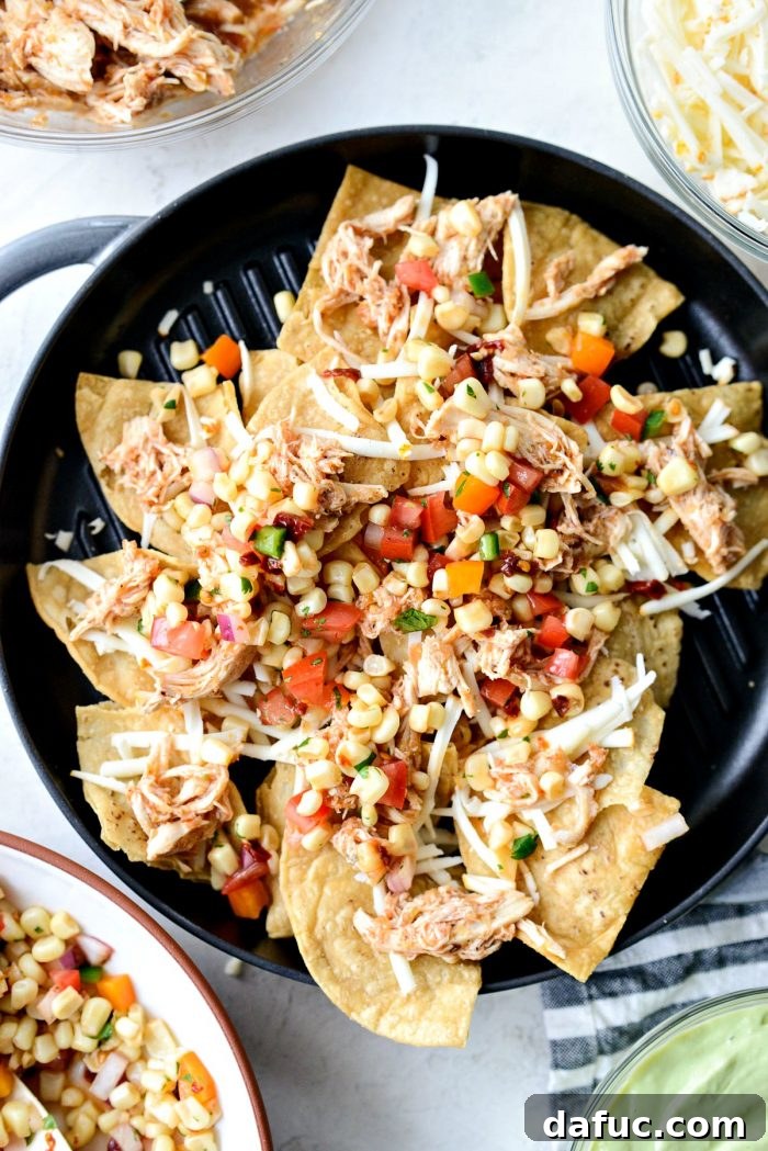 Golden Lava Chicken Nachos 6 First layer of Jacuzzi Chicken Nachos being assembled: crispy tortilla chips topped with shredded Jacuzzi chicken and Muenster cheese in a skillet.