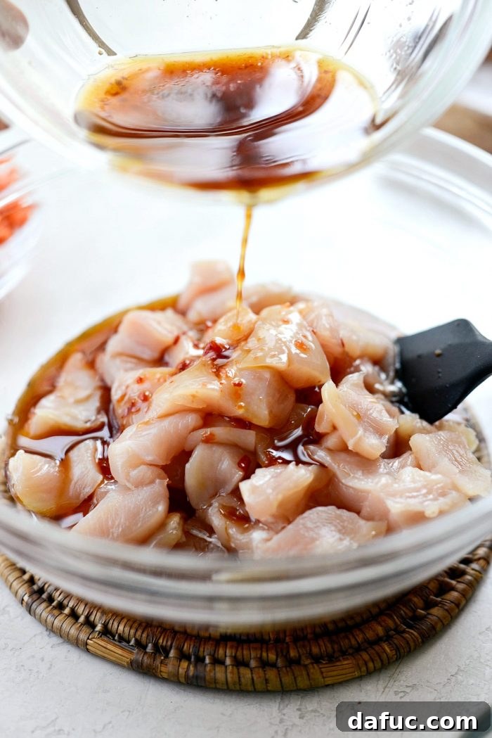 Pouring marinade/sauce over diced chicken breasts in a bowl
