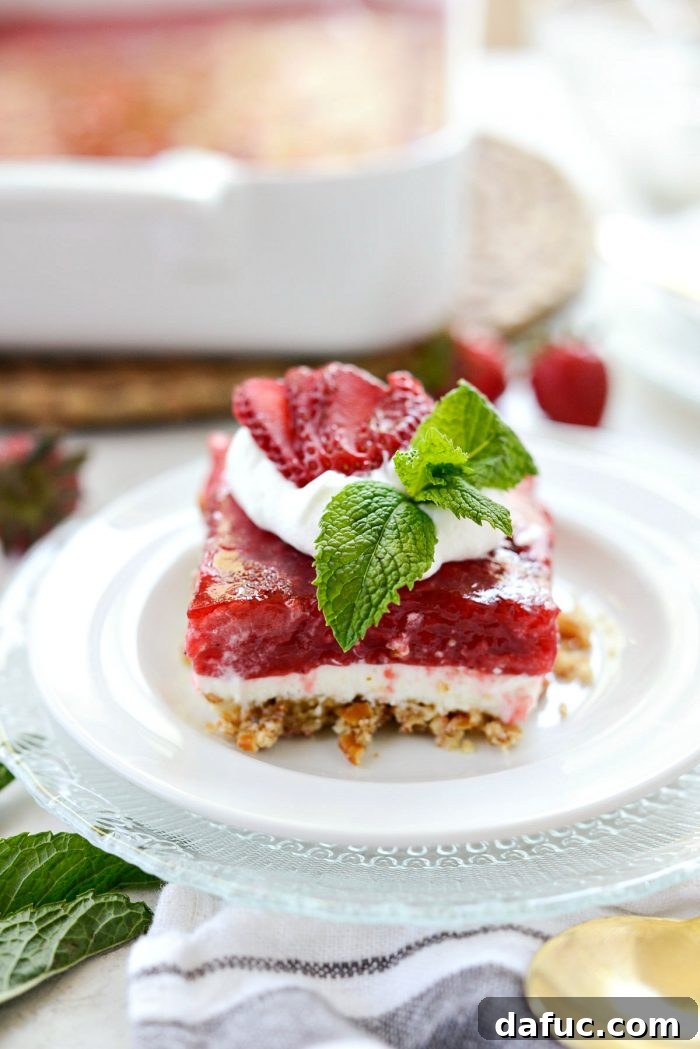 Front view of strawberry Pretzel Dessert Bars on white plate, showcasing the distinct layers.