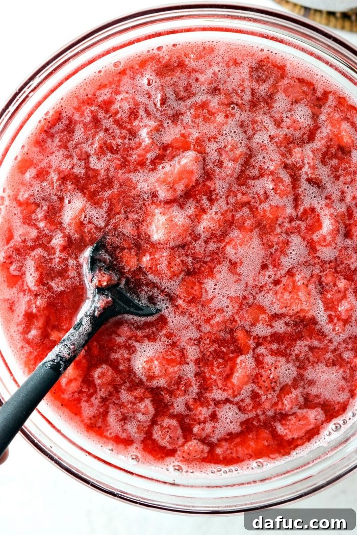 A bowl of chilled strawberry Jell-O mixture, now thickened to the perfect pouring consistency before setting completely.