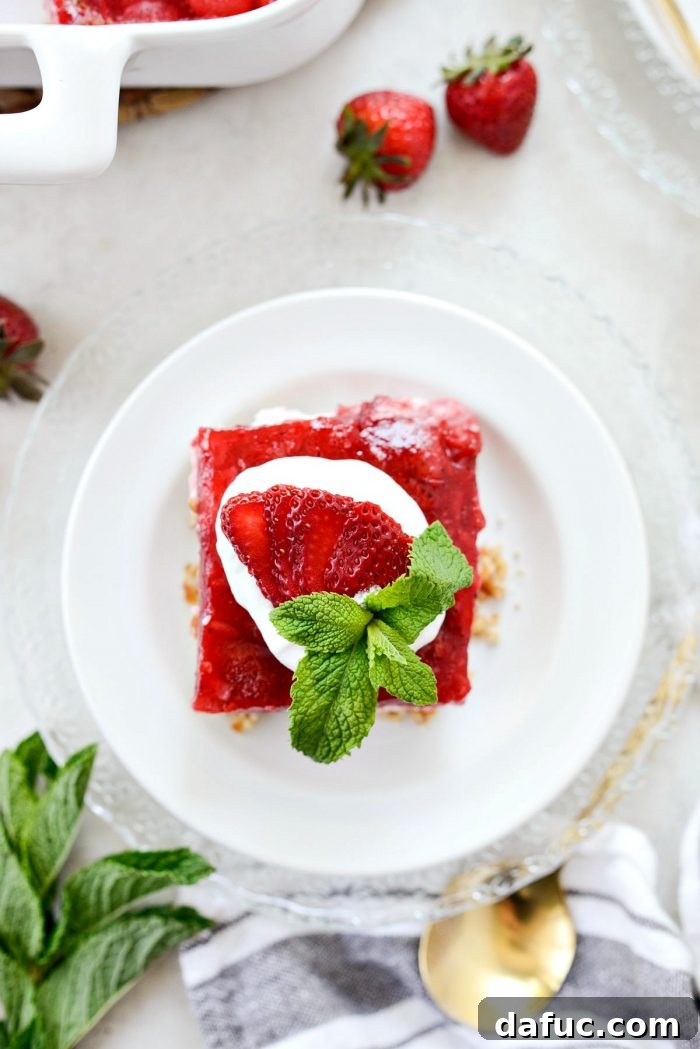 Looking top down on a perfectly layered strawberry pretzel dessert bar with a dollop of whipped cream on top.