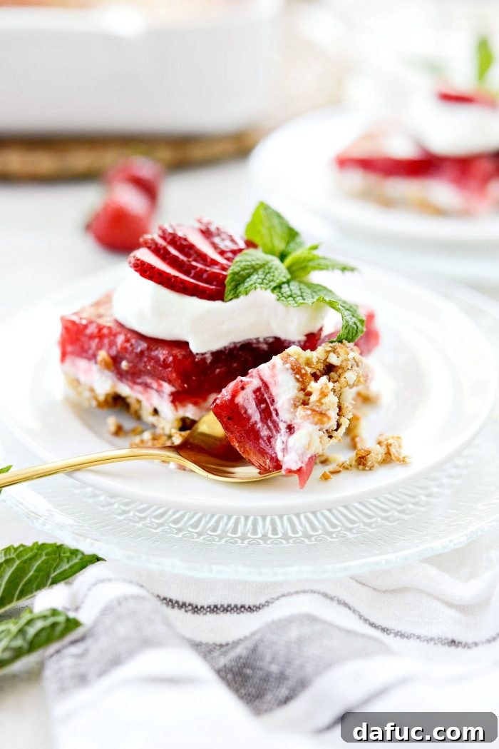 A perfect bite of strawberry pretzel dessert bar on a spoon, showing all the harmonious layers.