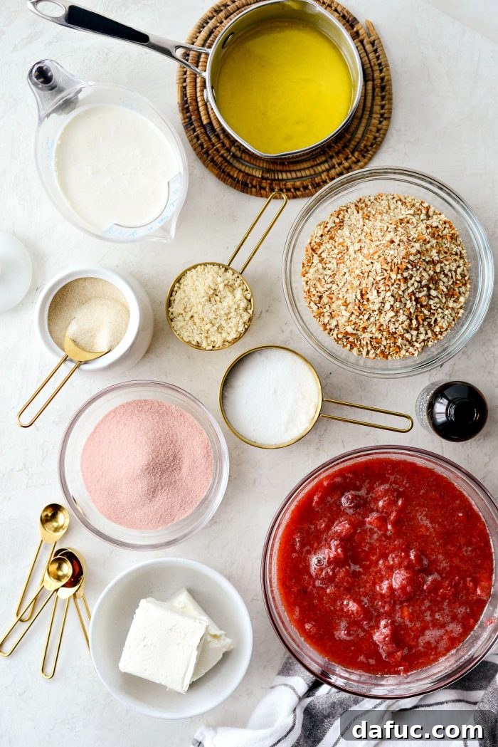 A collection of fresh ingredients laid out for strawberry pretzel dessert bars, including pretzels, almonds, sugar, butter, cream cheese, heavy cream, strawberry gelatin, and frozen strawberries.