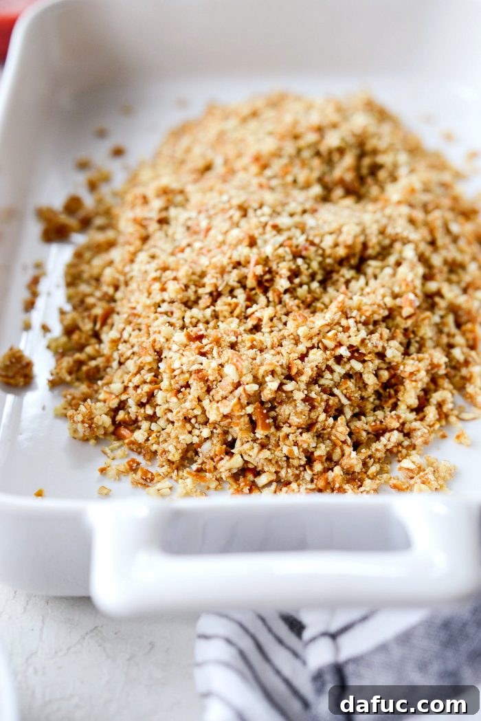 The pretzel almond crust mixture transferred to a white baking dish, ready for pressing and baking.