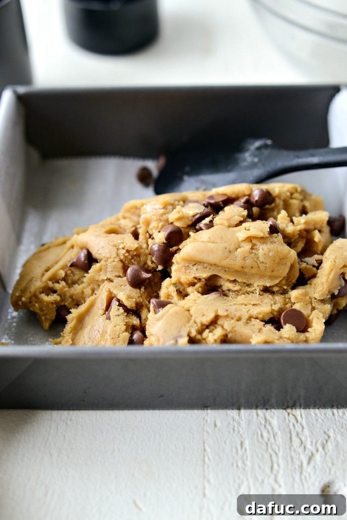 Golden Brown Butter Chocolate Chip Blondies 16 Blondie batter pressed evenly into a parchment-lined baking pan, ready for the oven.