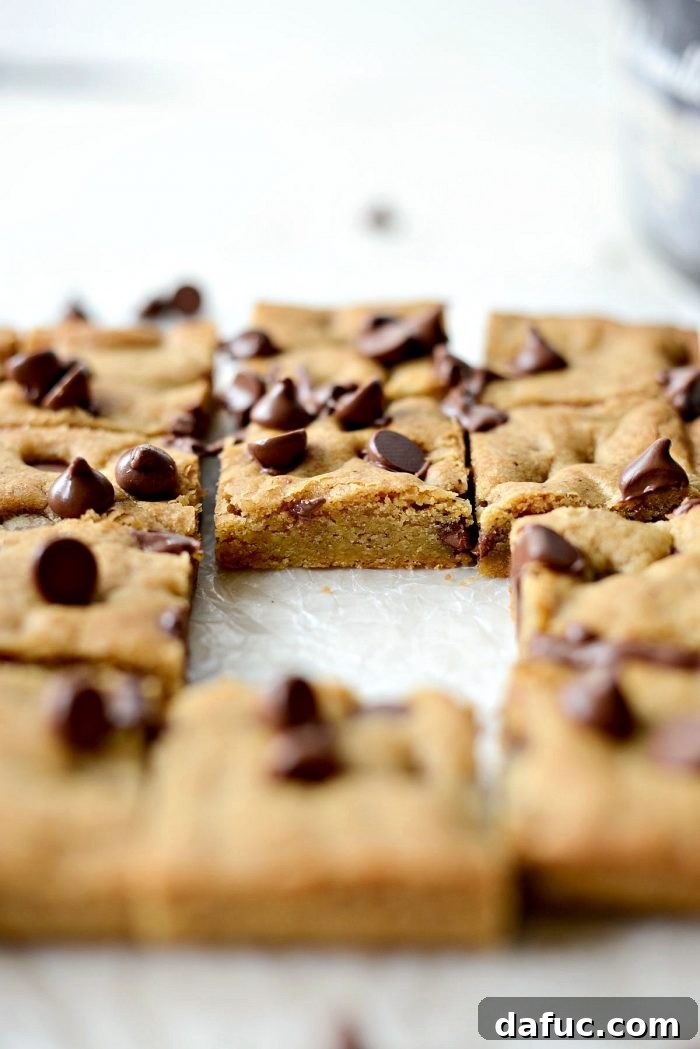 Golden Brown Butter Chocolate Chip Blondies 3 A close-up of a stack of golden brown butter chocolate chip blondies, emphasizing their chewy texture and abundance of chocolate chips.