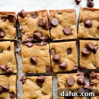 A square brown butter chocolate chip blondie on a white plate with a fork.
