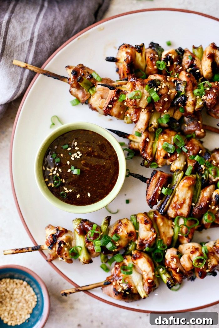 Platter of Chicken Yakitori skewers garnished with sesame seeds and green onions.
