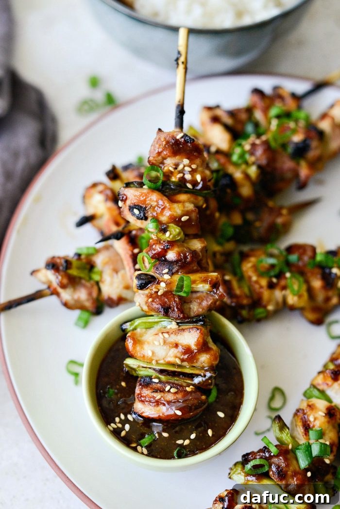 Close-up of freshly grilled Chicken Yakitori skewers, showing tender chicken and green onions with a sticky glaze.