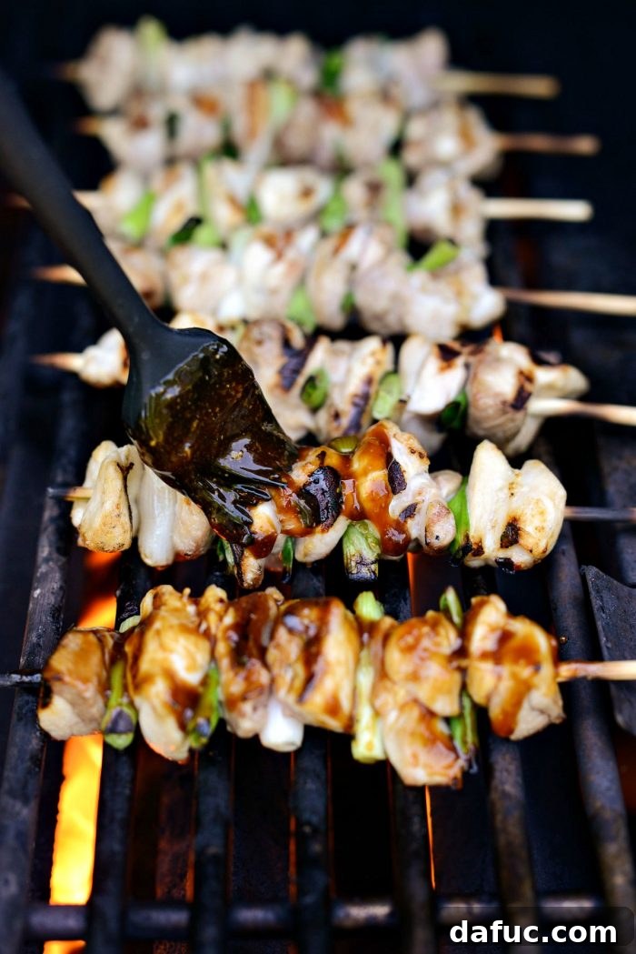Chicken Yakitori skewers cooking on a hot grill, showing early stages of grilling.