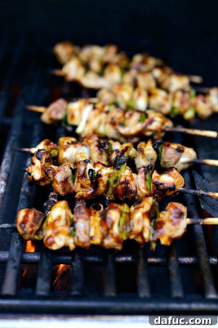 Grilled Chicken Yakitori skewers being basted with sauce on the grill.