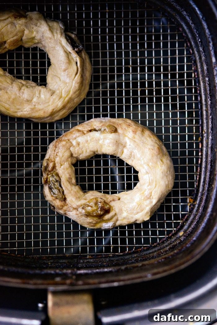 Homemade Air Fryer Cinnamon Raisin Bagels 23 bagel placed in air fryer basket.