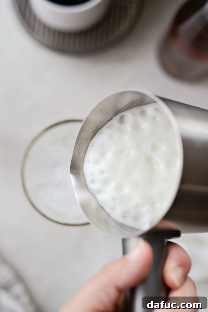 Velvet Caramel Vanilla Chill 11 A close-up view of frothy milk being poured into a glass, showcasing beautiful bubbles.