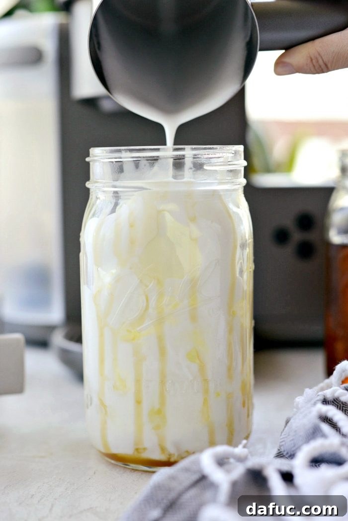 Velvet Caramel Vanilla Chill 12 Pouring frothed milk into a glass jar filled with ice.
