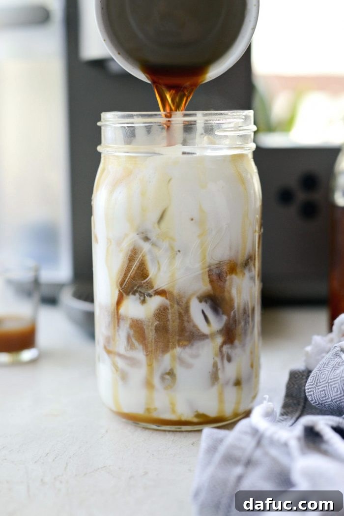 Velvet Caramel Vanilla Chill 13 Pouring sweetened espresso over frothed milk and ice in a glass jar.