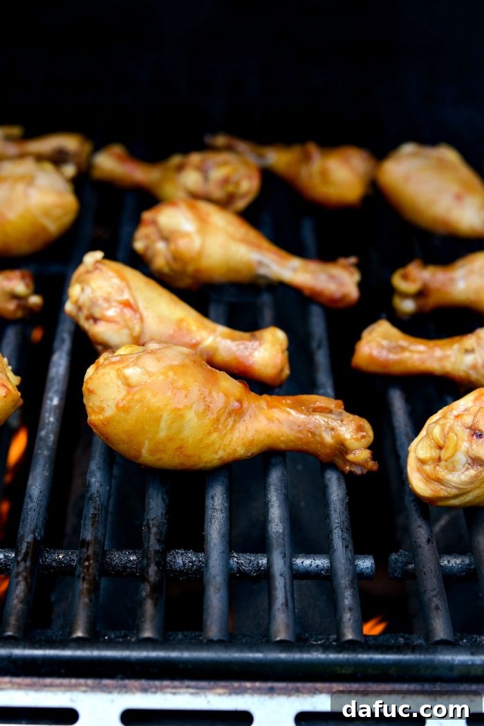 Sticky Sweet BBQ Drumsticks 11 Chicken drumsticks actively grilling on hot grates, showing early signs of charring and grill marks.