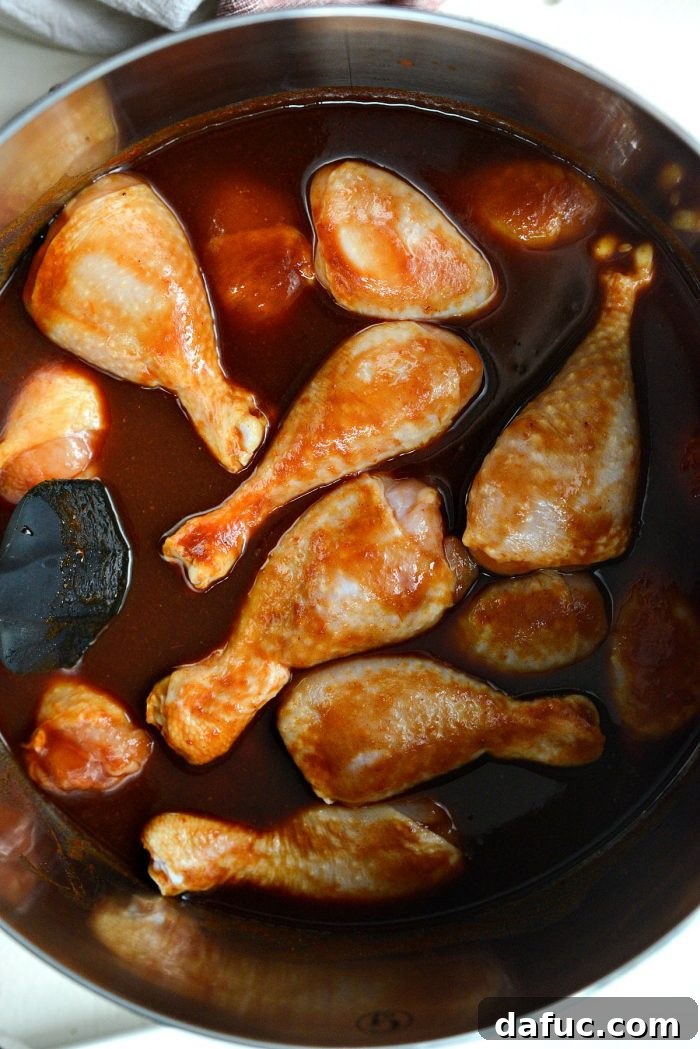 Sticky Sweet BBQ Drumsticks 7 Chicken drumsticks being tossed thoroughly in the rich homemade barbecue sauce, ensuring an even coating before simmering.
