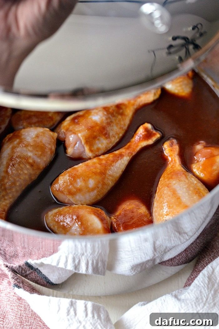 Sticky Sweet BBQ Drumsticks 8 The pot of chicken drumsticks simmering in barbecue sauce, covered with a lid to ensure even cooking and moisture retention.