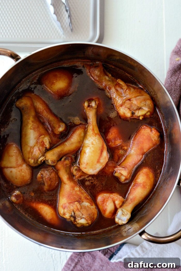 Sticky Sweet BBQ Drumsticks 9 Fully cooked chicken drumsticks resting in the rich, dark homemade barbecue sauce within the pot, ready to be transferred to the grill.