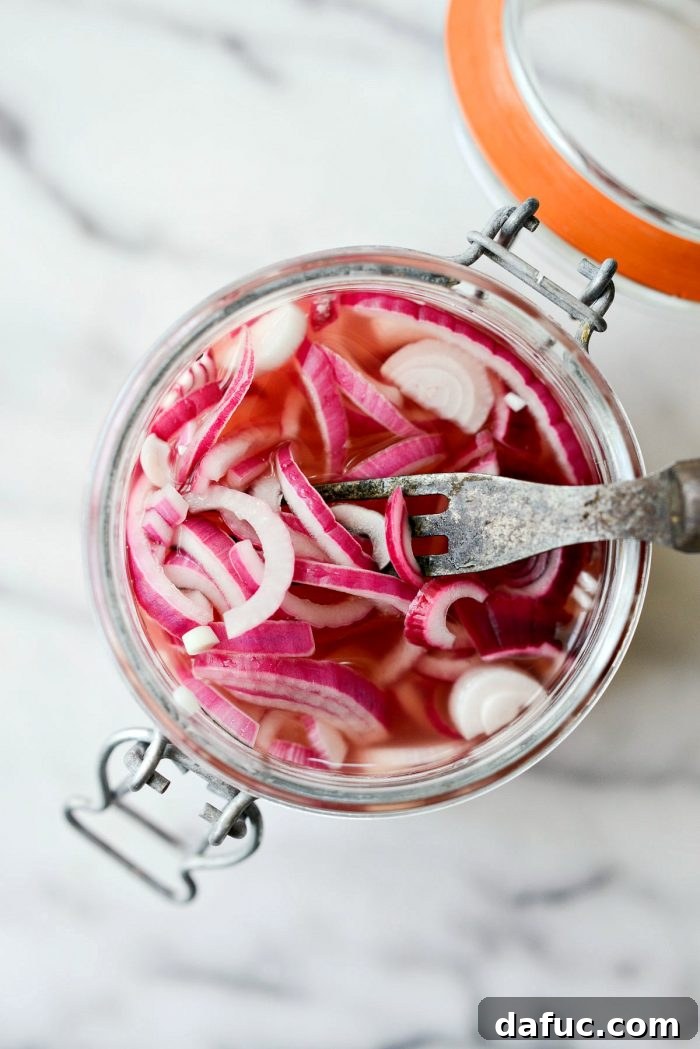 Zesty Quick Pickled Red Onions 2 Close-up of a fork lifting brightly colored quick pickled red onions from a jar