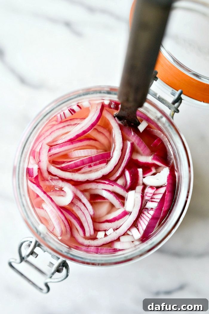 Zesty Quick Pickled Red Onions 13 Looking down into a glass jar filled with bright pink quick pickled red onions