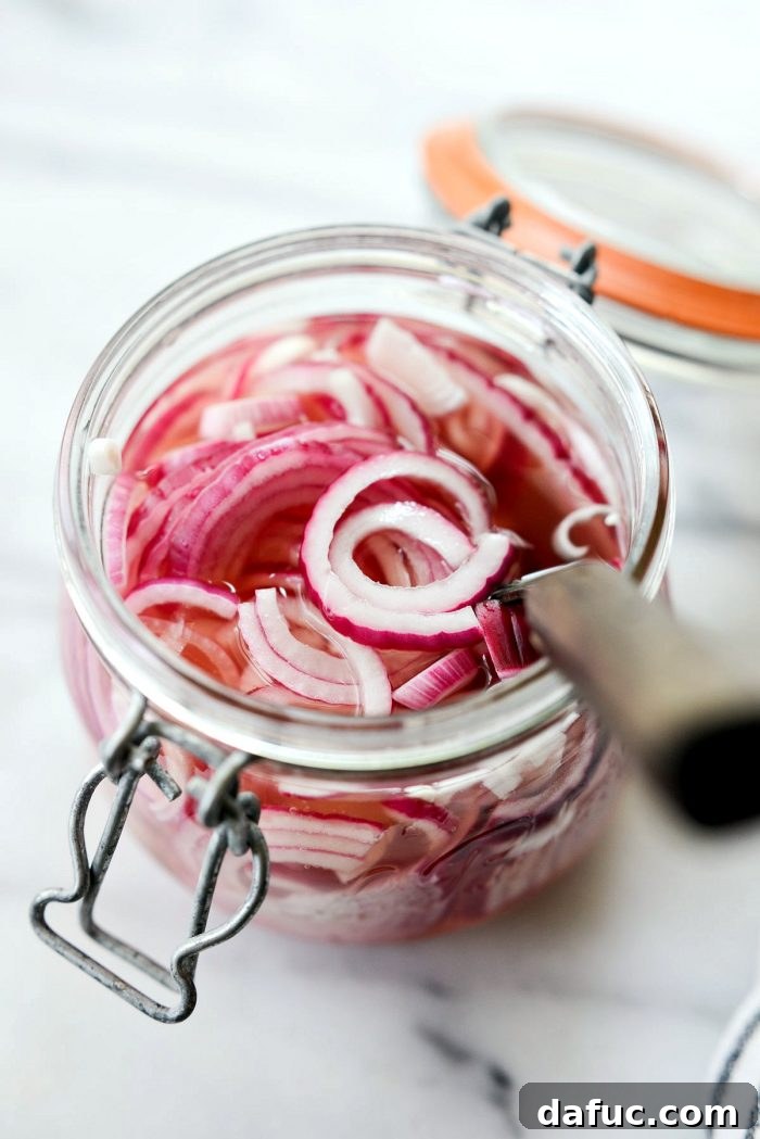 Zesty Quick Pickled Red Onions 16 A glass jar of quick pickled red onions with a fork inside, ready for serving
