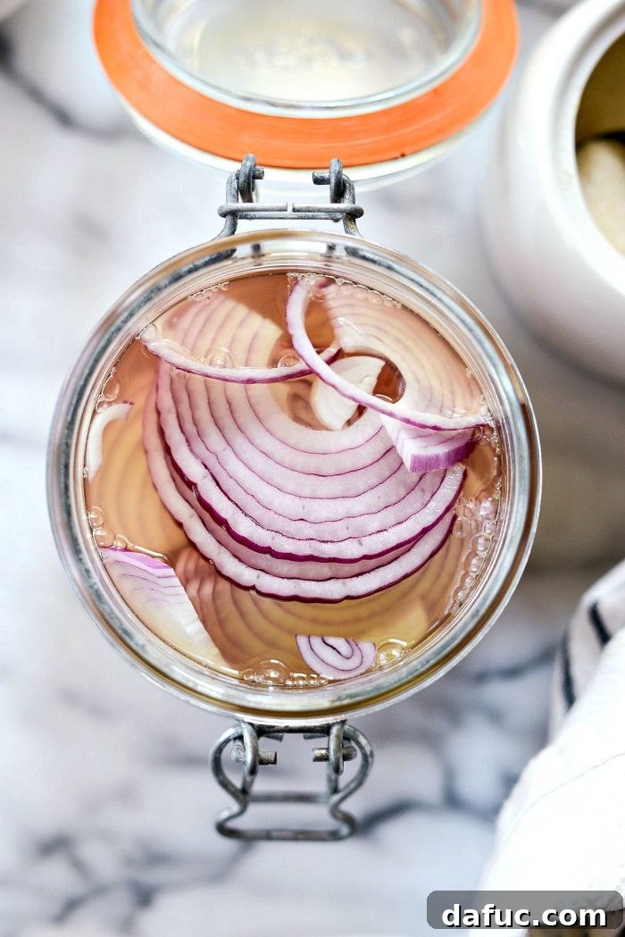 Zesty Quick Pickled Red Onions 8 Ensuring sliced red onions are fully submerged in the pickling liquid within the jar