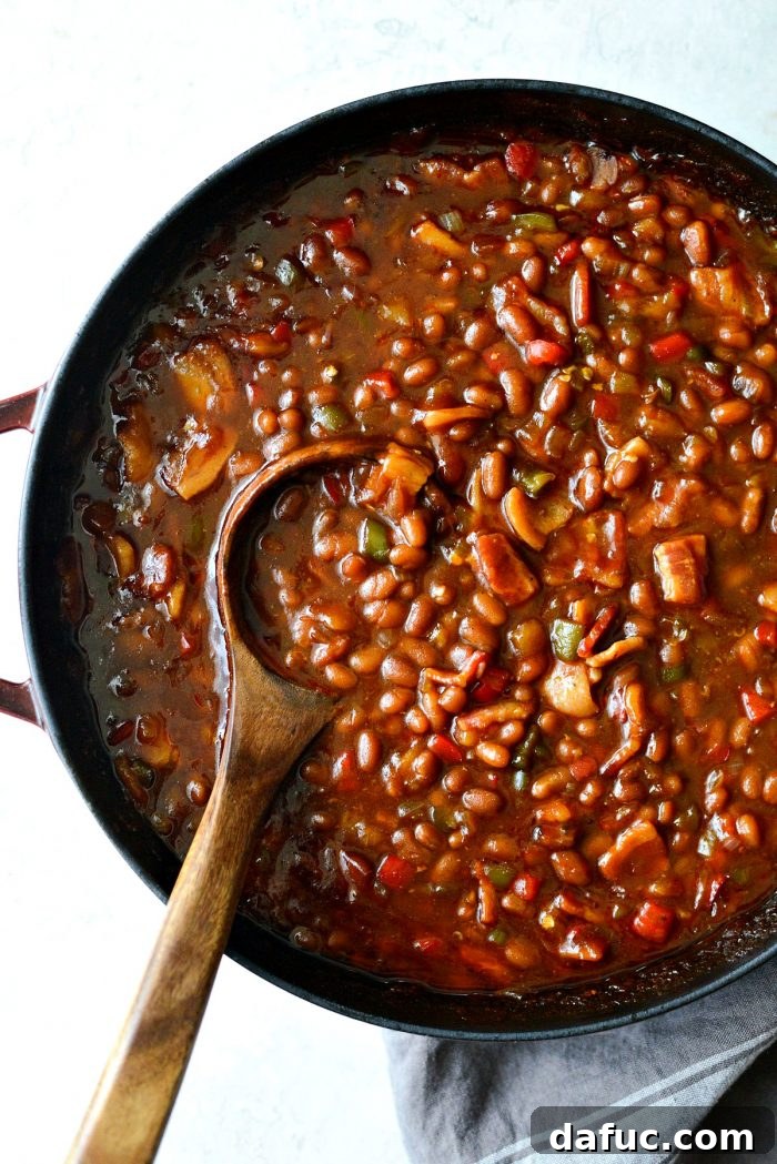 One Pot Wonder Baked Beans 14 a wooden spoon resting in the red pot filled with one pot wicked baked beans, ready for serving