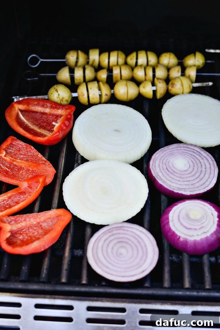 Potatoes, onions, and bell peppers grilling together on a hot grill.
