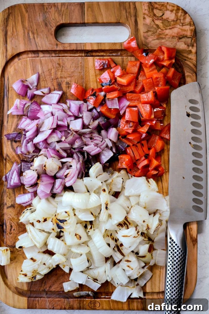 Roughly chopped grilled bell pepper and onions on a cutting board.