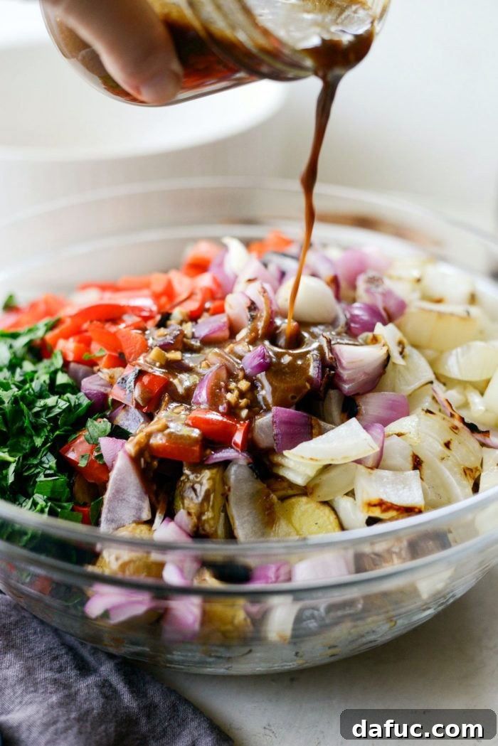 Pouring the balsamic dijon dressing over the salad ingredients in the bowl.