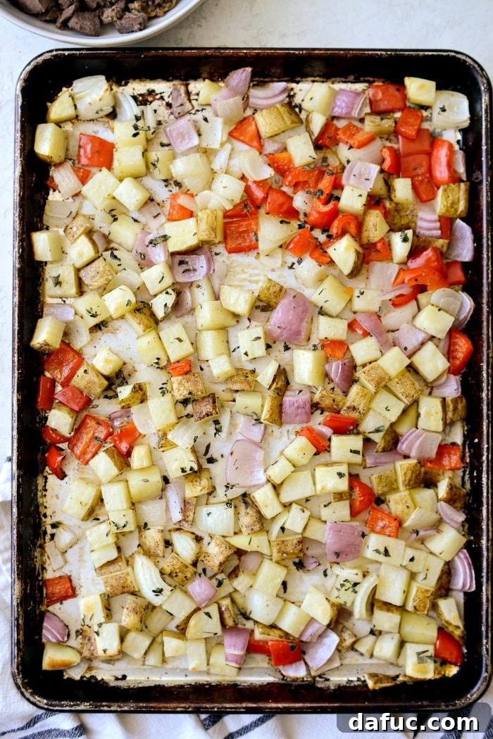 Smoked Brisket Breakfast Hash 6 Diced potatoes, red bell pepper, and onions tossed in olive oil and fresh herbs on a baking sheet, ready for the oven.