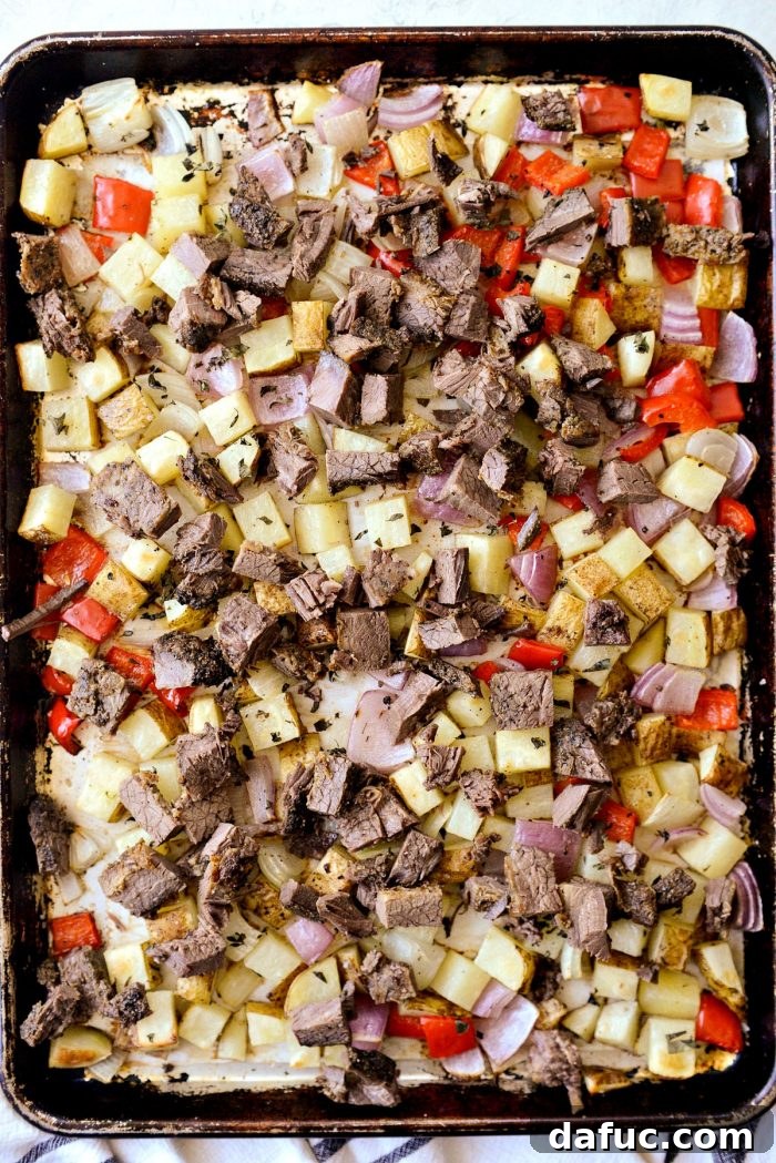 Smoked Brisket Breakfast Hash 8 Sheet pan with roasted vegetables and diced smoked brisket scattered on top, warming in the oven.