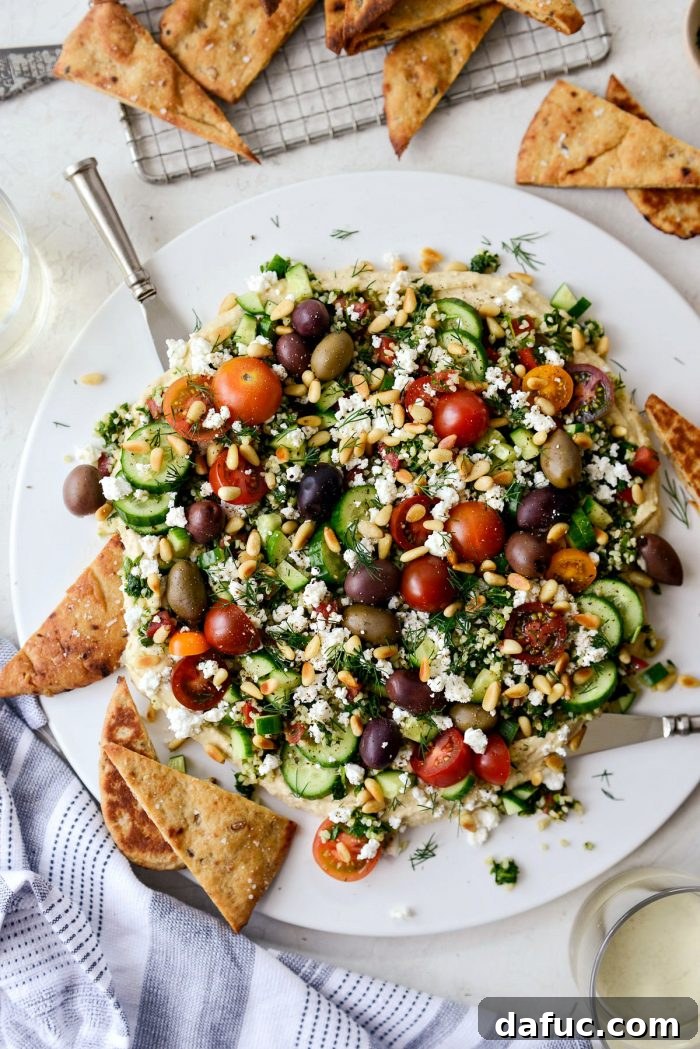 Vibrant 7-Layer Loaded Hummus Dip with fresh toppings and toasted naan