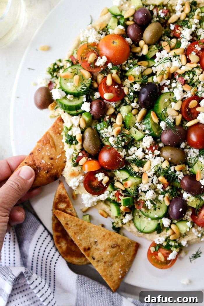 Close-up of a naan dipper scooping the layered hummus dip
