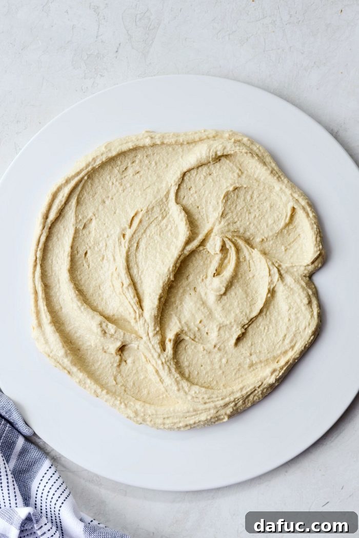 Smooth hummus spread on a white serving platter