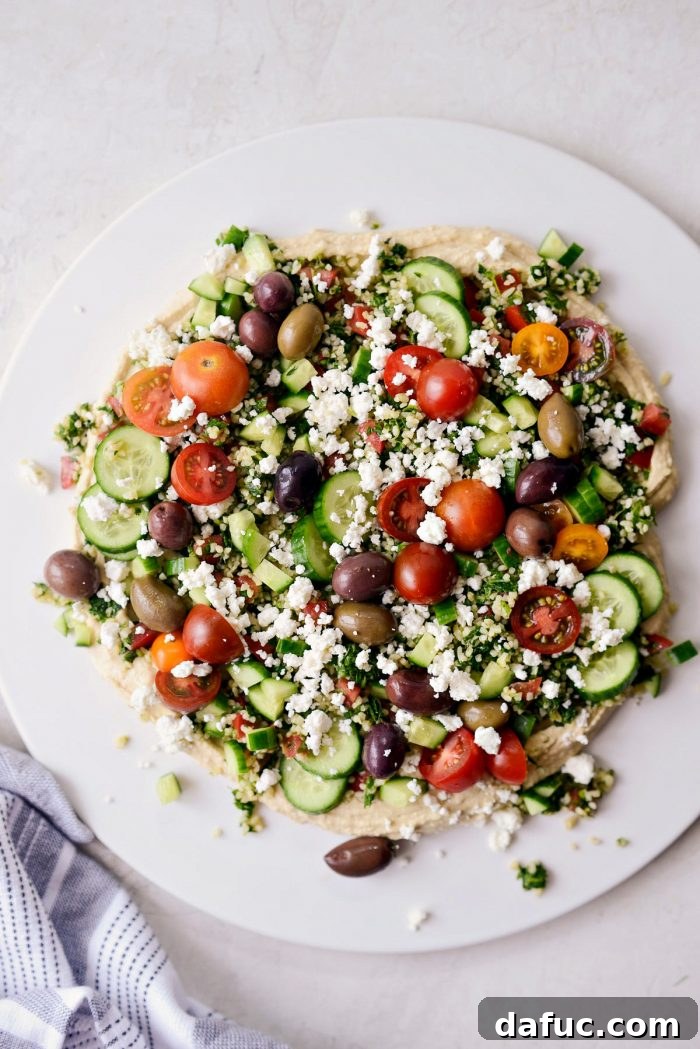 Loaded hummus dip with fresh tomatoes, feta, and olives added