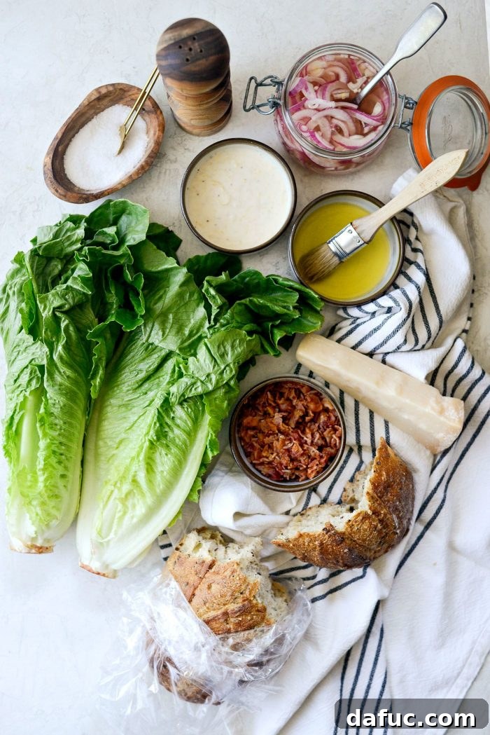 A vibrant display of fresh ingredients for Grilled Romaine Salad, including whole romaine heads, bacon, lemon, and cheese