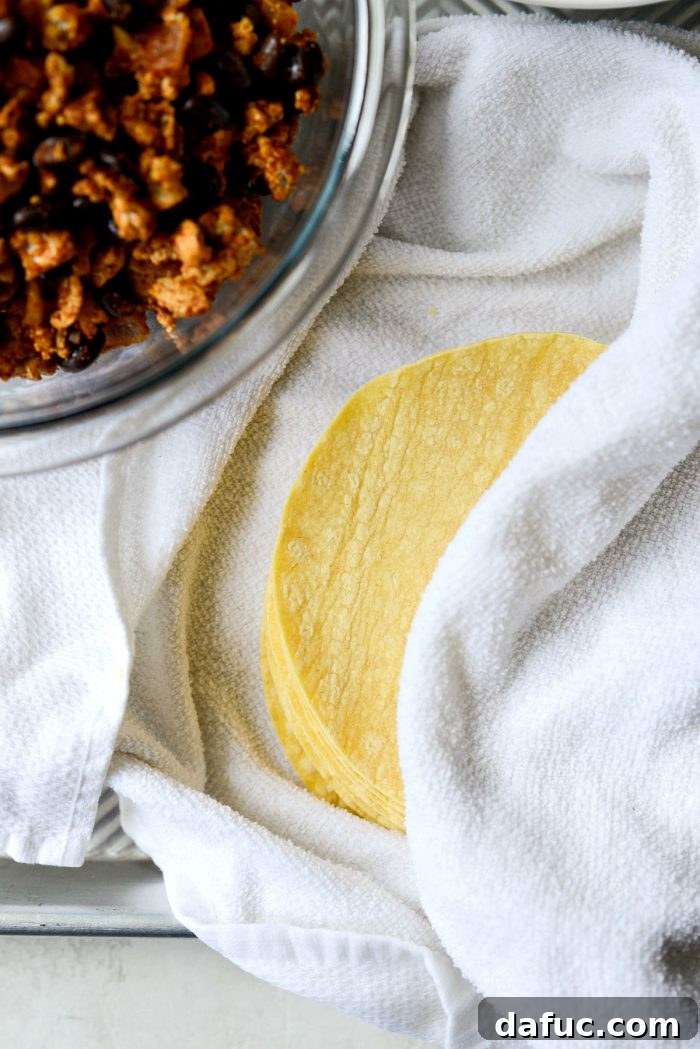 Corn tortillas wrapped in a damp kitchen towel, ready for warming in the microwave.