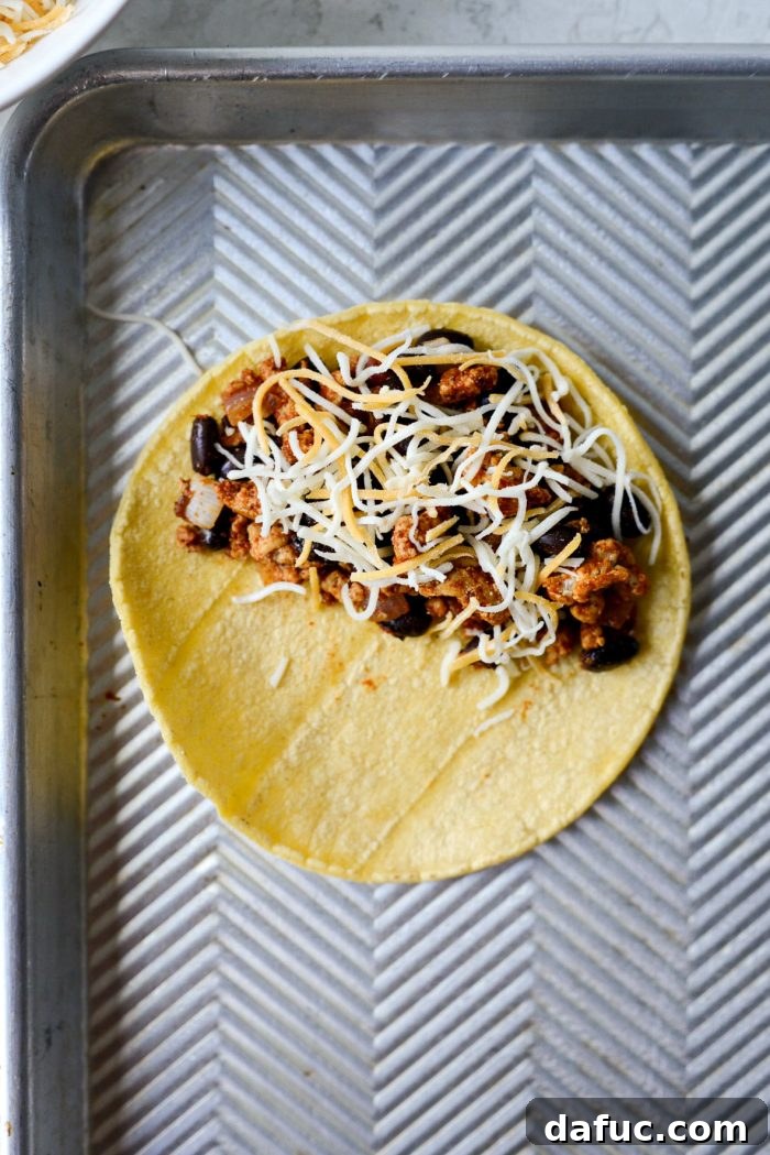 A corn tortilla filled with chipotle chicken and black bean mixture and shredded cheese, folded in half.