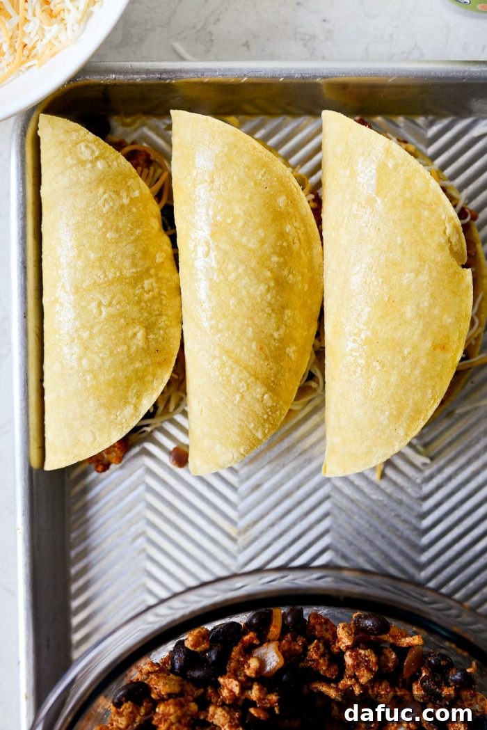 Three folded tacos, lightly sprayed with olive oil, ready to be placed in an air fryer.
